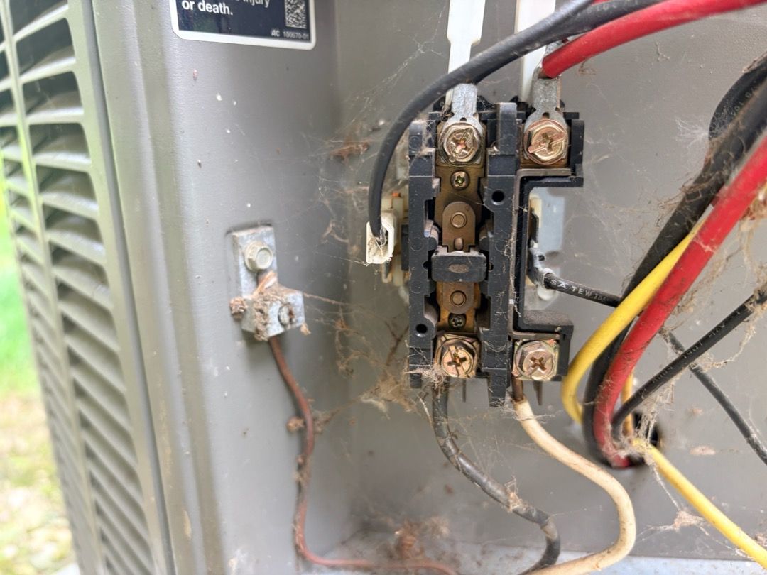 A worn, cobwebbed contactor found inside an air conditioner during service